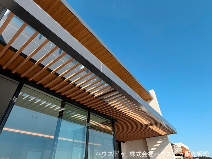 光と影をデザインする木製ルーバー。 青空と調和するモダンな外観が、温かみのある表情を見せる。細部にまでこだわった、洗練された建物です。(2025年10月撮影)