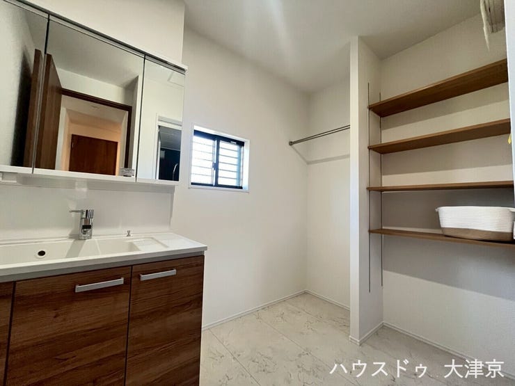 収納棚とハンガーパイプを備えた洗面室。衣類管理がしやすく、家事がスムーズに進む使い勝手の良い空間です。