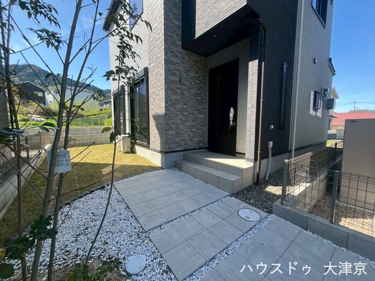 外壁の質感と植栽の緑が調和し、住まい全体に豊かな表情を生む外構。