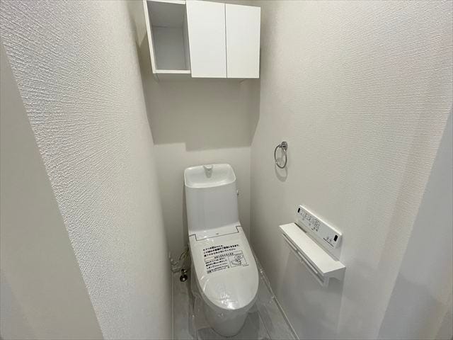 1階トイレ:玄関近くに完備されています。白色の壁紙で清潔感のあるスッキリとした空間。