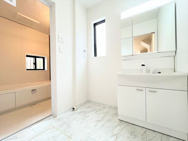 白基調の洗面スペースはすっきり上品な印象で、三面鏡があることで使い勝手も優れた空間になっています。