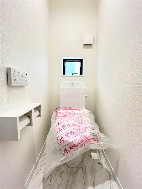 白を基調としたシンプルな壁紙のトイレです。小窓の手前には芳香剤を置いたり小物を置くことができますね。