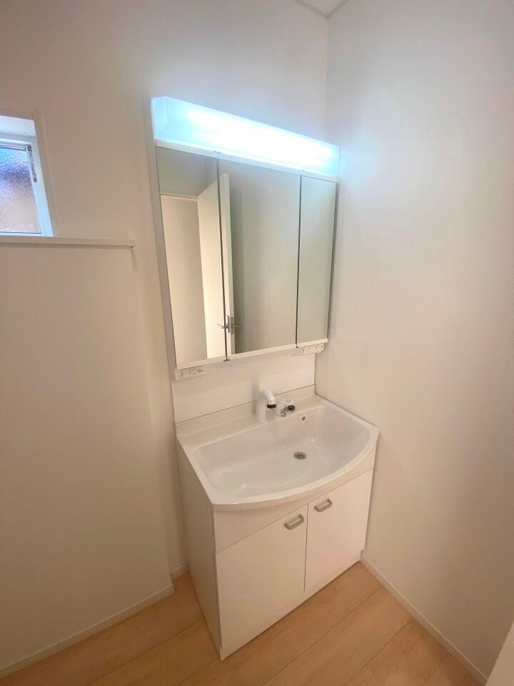 収納力に優れた三面鏡の洗面化粧台。シャワー機能付きで衣類の手洗いや洗髪にも活躍します。