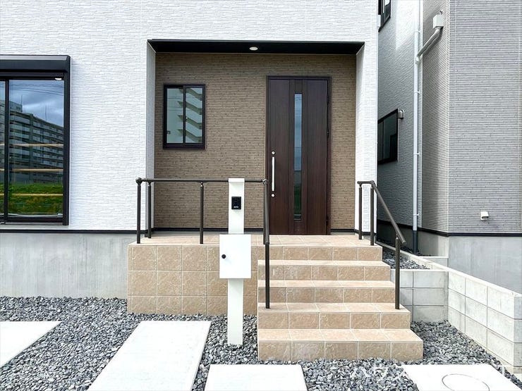 レンガ調のアプローチ階段がお洒落なエントランス。玄関ドアのデザインと外壁との調和が取れた配色になっています。