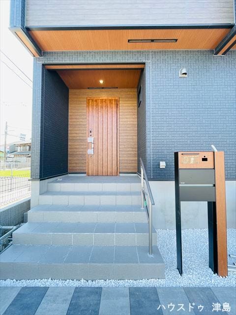 玄関ポーチは照明付きで暗い時間帯の帰宅も安心。表札・インターホン・ポストが一体型になった門柱。