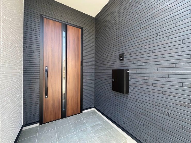 木目調のドアとシックな外壁が調和した、落ち着きのあるスタイリッシュな玄関です。