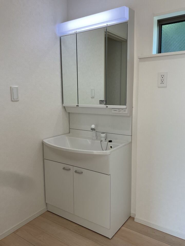 清潔感のある白い洗面化粧台。すぐ横は洗濯機置き場です。キッチンから引き戸で導線が確保されていますので家事の軽減につながります。