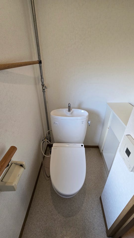 快適な温水洗浄便座付きトイレ。手すりや便利な収納棚が備え付けられており、快適さと安全に配慮された空間です。