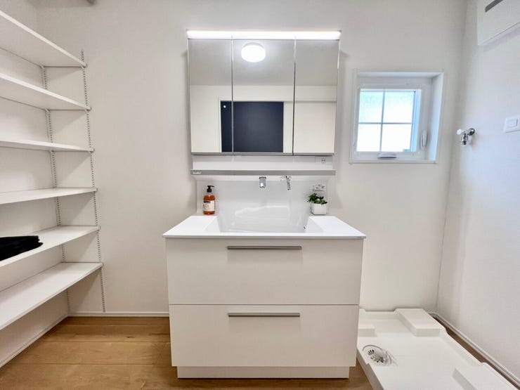 白を基調とした清潔感のある洗面室。三面鏡収納付きの洗面台で、細かな身支度用品もすっきり整理できます。窓付きで明るく、湿気がこもりにくい点も魅力です。