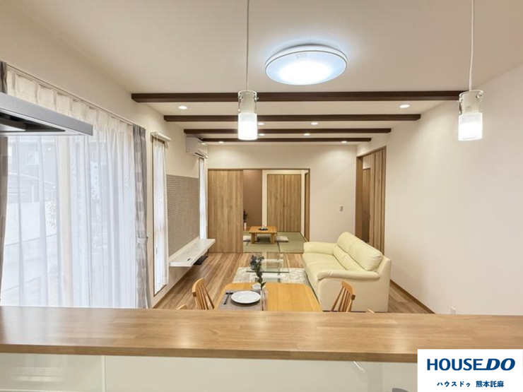 木の梁がおしゃれな、開放感あるLDK。対面キッチンから家族の様子が見守れます。奥の和室と繋げば大空間に。団欒のひとときを彩る、心地よいリビングです。