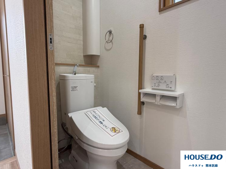 温水洗浄便座付きの清潔なトイレ。手洗い付きタンクや手すりも完備し、幅広い世代に配慮した設計。快適に使える機能的な空間です。