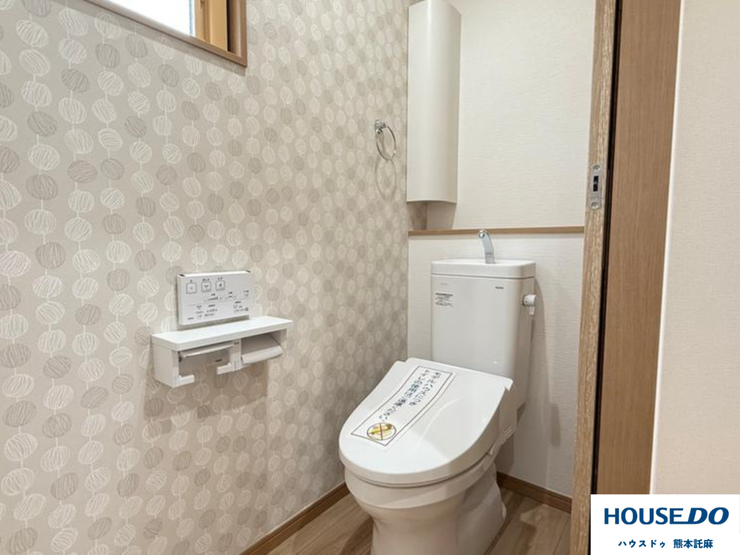 アクセントクロスがお洒落な温水洗浄トイレ。収納と窓も完備し、清潔感とデザイン性を両立。細部まで快適さにこだわった空間です。