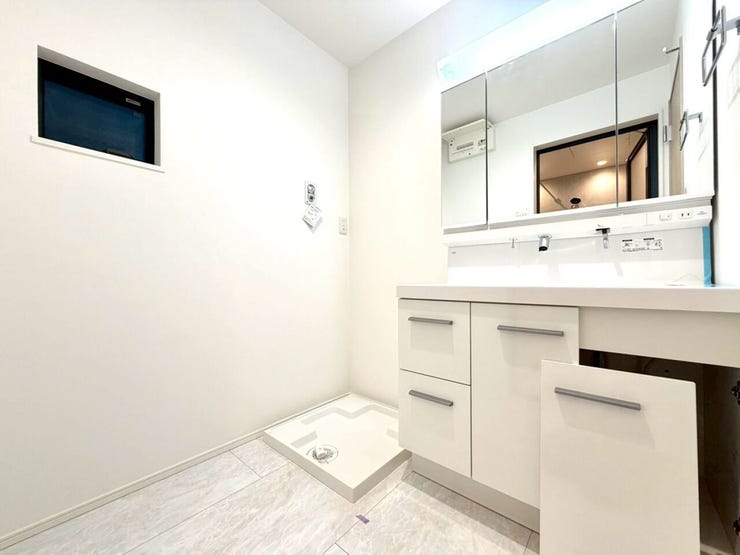 三面鏡付き洗面台と洗濯機置場を完備した、ゆとりある洗面スペース