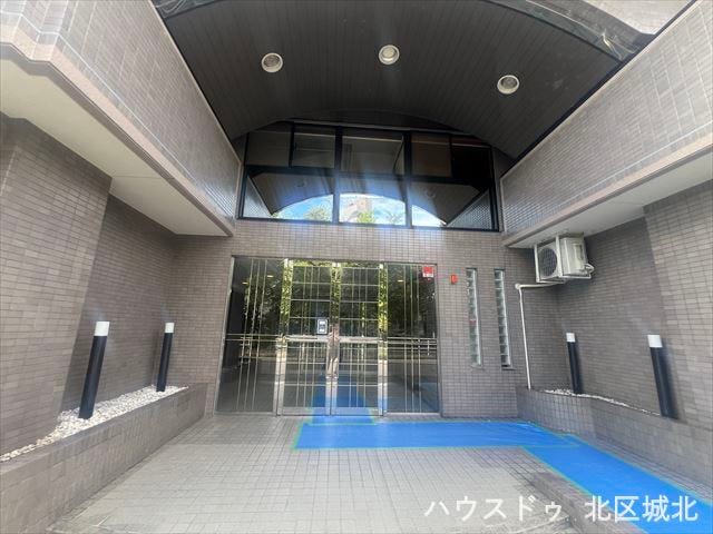 モダンなデザインが特徴のマンションエントランス。広々としたアプローチとガラス扉が開放感を演出し、落ち着いた色合いの外壁が高級感を醸し出しています。