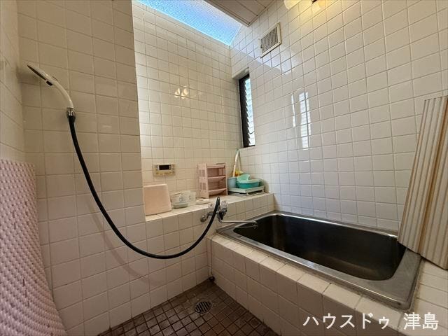 白いタイルが施工された浴室です。窓から明かりが差し込み、明るいうちからバスタイムでリラックスできそうです。