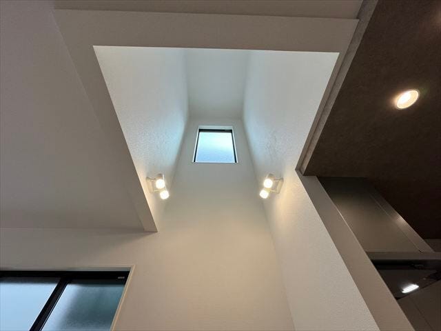 高い天井がもたらす圧倒的な開放感。上部の窓から光が差し込み、家全体を明るく、心地よい空間にします。