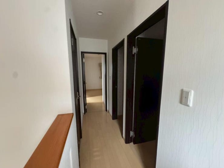 清潔感のあるホワイトと、引き締まったダークブラウンの扉がモダンな雰囲気を演出する廊下です。