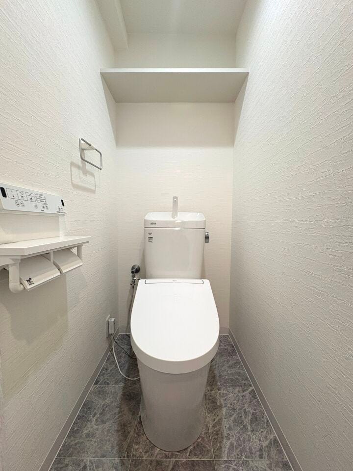 温水洗浄便座付トイレ。上部収納棚にはトイレットペーパーや掃除用品も保管できますね。