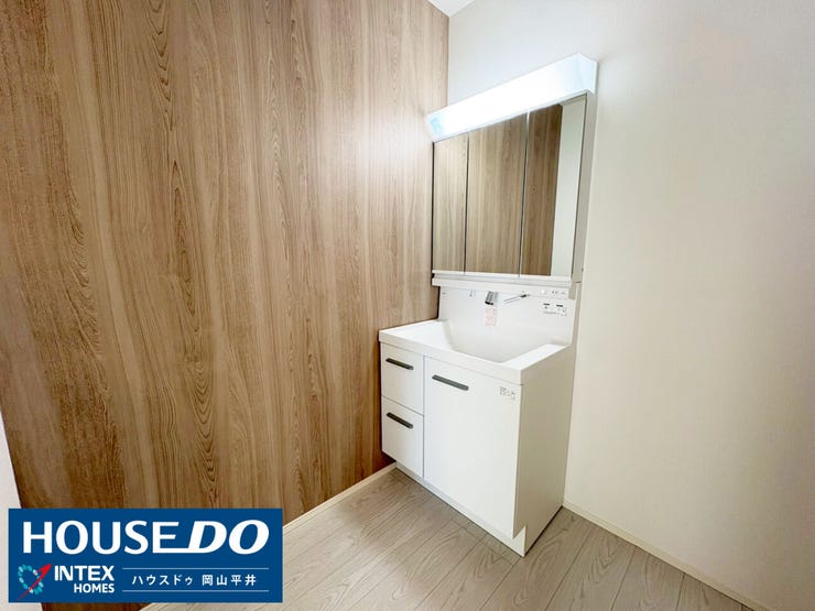 ナチュラルな木目調の壁紙が目を引く、お洒落な洗面室。三面鏡の裏や足元のスライド収納など、家族全員の小物もスッキリ片付きます!朝の身支度も心地よくスムーズに♪