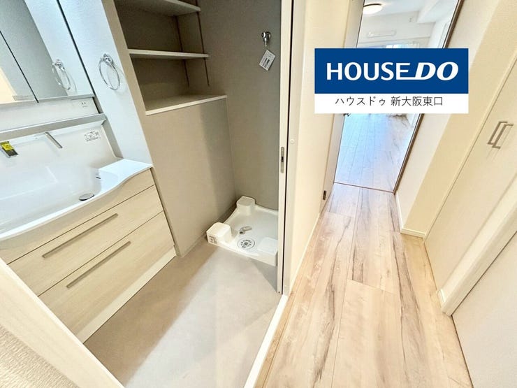 三面鏡のシャンプードレッサーと洗濯機置き場と収納棚がある洗面所です。