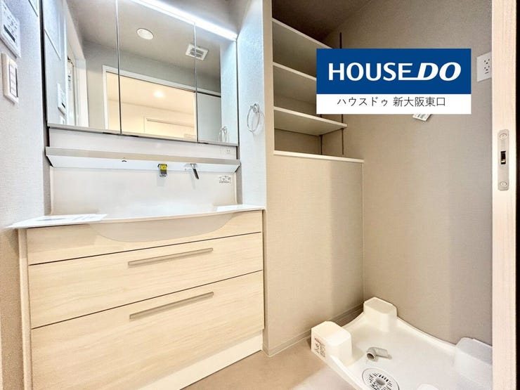 三面鏡のシャンプードレッサーと洗濯機置き場と収納棚がある洗面所です。