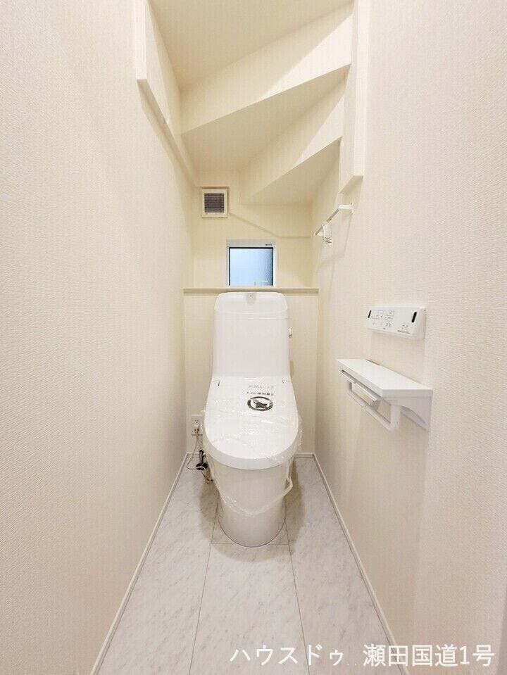 白を基調とした清潔感のあるトイレです。後方にはちょっとした小物を飾れるスペースがあります。