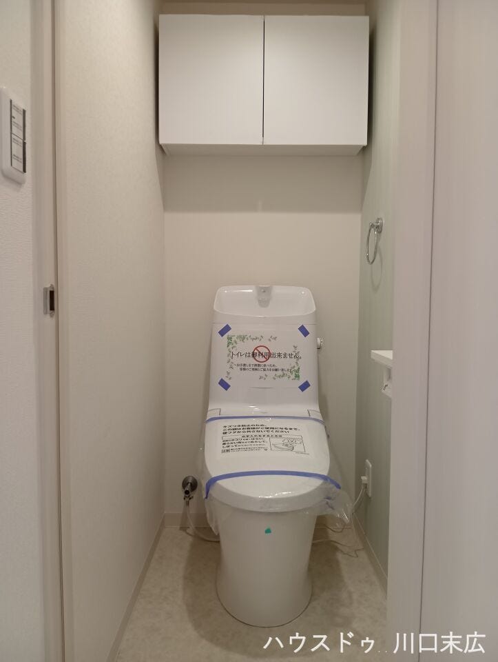 手洗い付きタンクを備えた機能的なトイレ空間。上部には扉付きの吊戸棚を設置し、トイレットペーパーなどを隠して収納できます。