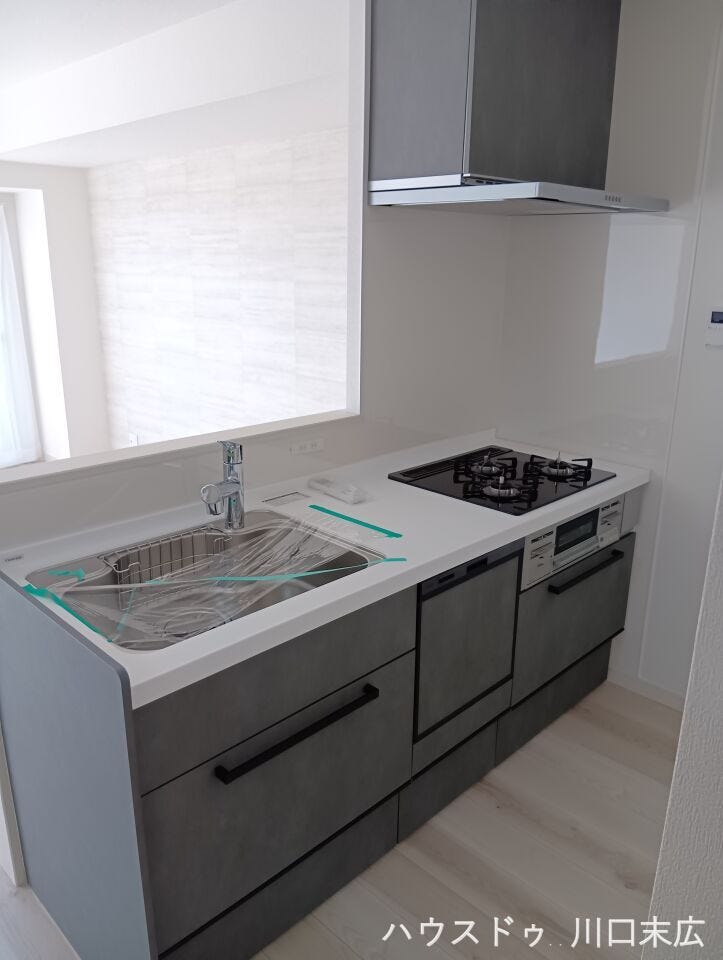 リビングを見渡せる対面式システムキッチン。シックなグレーの面材が空間を引き締め、都会的でモダンな印象を与えます。