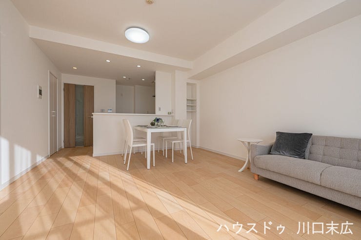 ダウンライトが空間を優しく照らすLDK。対面式キッチンを備え、料理中も家族との会話が弾む設計です。フローリングの温かみが、くつろぎの時間を演出します。