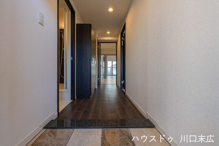 玄関を開けた瞬間に広がる、高級感ある石目調のタイルと木目のコントラスト。帰宅するたびに心が安らぐ、上質な住まいの顔となる空間です。