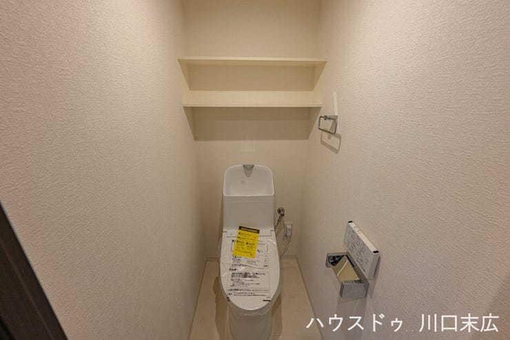 清潔感のあるホワイトで統一されたレストルーム。上部には収納棚が設けられており、トイレットペーパーや掃除用品をすっきりと収められます。