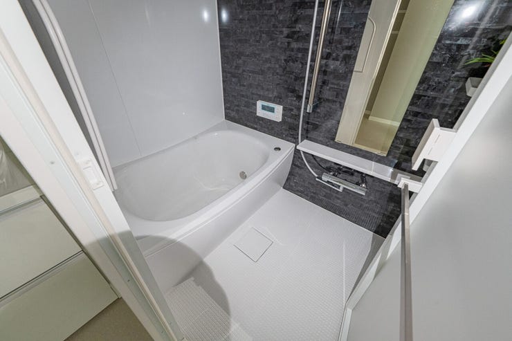 高級感あるダークトーンのパネルが、くつろぎのバスタイムを演出。横長の鏡が空間に奥行きを与えます。手すりや棚を備え、使い勝手と安全面に配慮された癒やしの空間です。