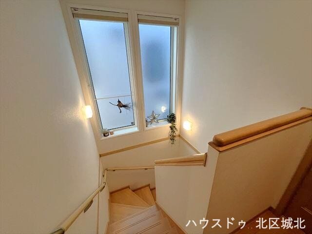 大きな窓からやわらかな光が差し込む明るい階段スペース。手すり付きで上り下りも安心でき、壁面ライトが夜間の移動を優しくサポートする、安全性と心地よさを兼ね備えた設計です。