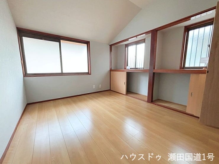 複数の窓から光が入り、室内は明るく開放的です。明るい木目のフローリングと、シンプルな壁紙が温かみのある空間を創り出しています。