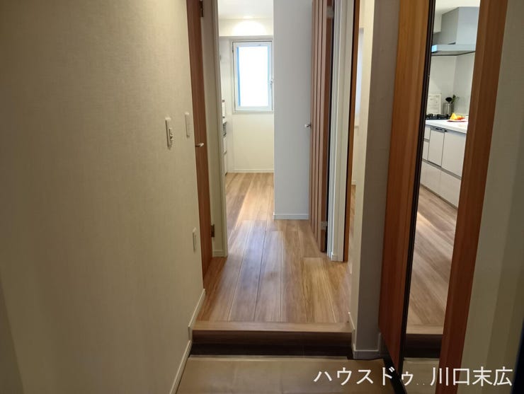 木目の美しさが引き立つフローリングが続くアプローチ空間。各居室への動線を繋ぎ、日々の出入りを穏やかに演出する落ち着いた設えです。