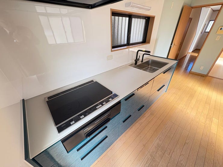 落ち着いたネイビーグレーのパネルと、ブラックの蛇口・IHクッキングヒーターが調和したモダンなデザインです。