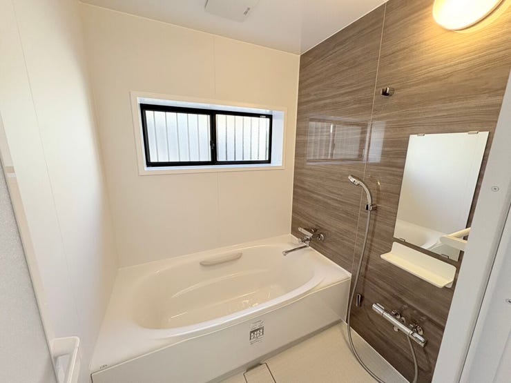 木目調パネルの癒やしバスルーム
壁一面に高級感のあるダークブラウンの木目調パネルを採用。視覚的な温もりがあり、リラックスしたバスタイムを演出します