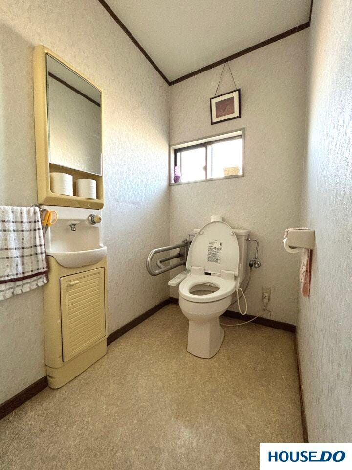 手すりや鏡付きの独立手洗い場を備えた、機能的で安心感のあるトイレです。窓からの自然光で室内は明るく、換気もしやすいため清潔に保てます。ゆとりある広さで、快適な毎日をサポートする空間です。