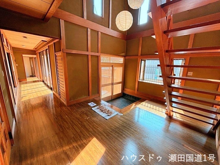 天井まで伸びる吹き抜けと木の梁が美しい玄関。自然光がたっぷり差し込み、訪れる人をやさしく迎え入れます。