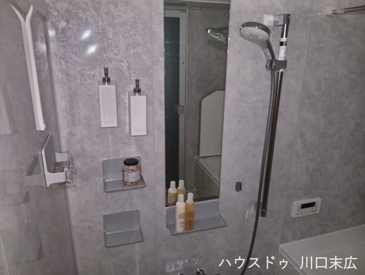 高級感のあるパネルが寛ぎを演出するバスルーム。スライドバー付きシャワーや棚を備え、使い勝手の良さにも配慮されています。