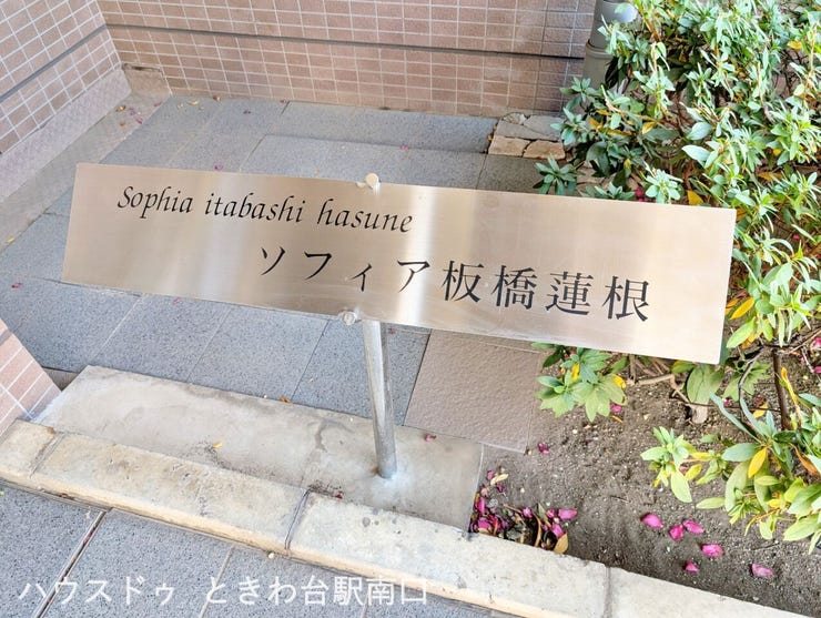 エントランス前に設置された館銘板は、ステンレス調で上品な佇まい。来訪者にも分かりやすく、建物全体の品格を高めています。
