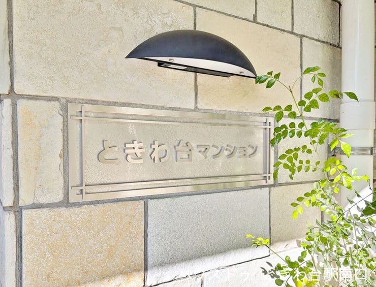 シンプルなデザインの館銘板。植栽と照明が配置され、帰宅時にほっとする雰囲気を演出しています。