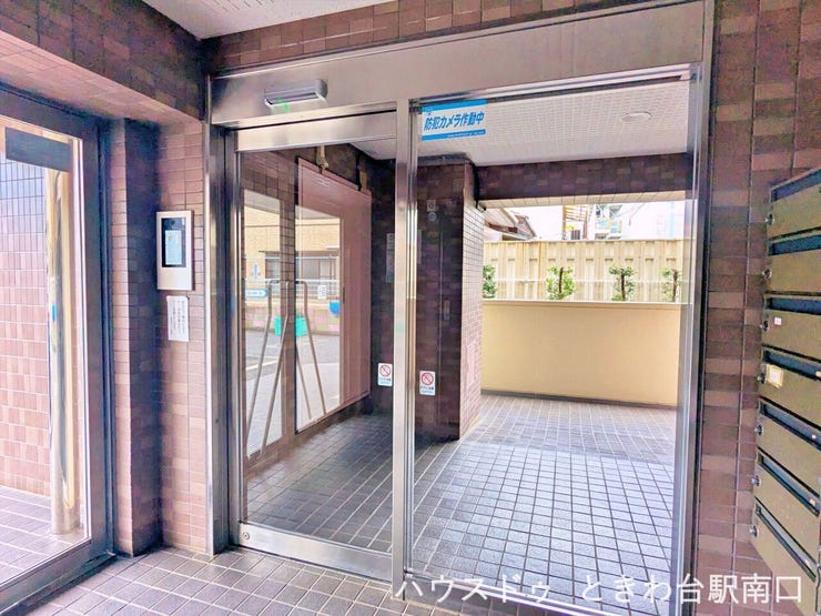 明るく開放的なエントランスホールです。防犯カメラが作動しており、セキュリティ意識の高さがうかがえます。自動ドアの先にはオートロックが設置されており、都会的な利便性と安心感を両立した空間です。