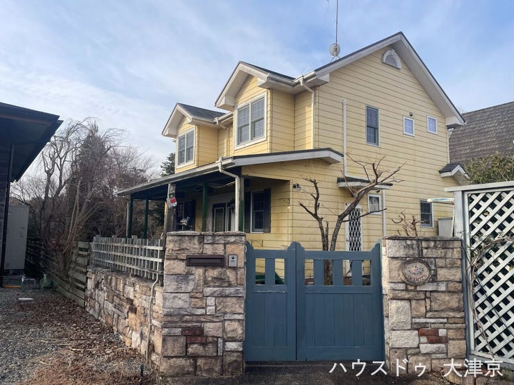 青い門扉と石積みが映える、イエローが鮮やかな北米風スタイルの家。