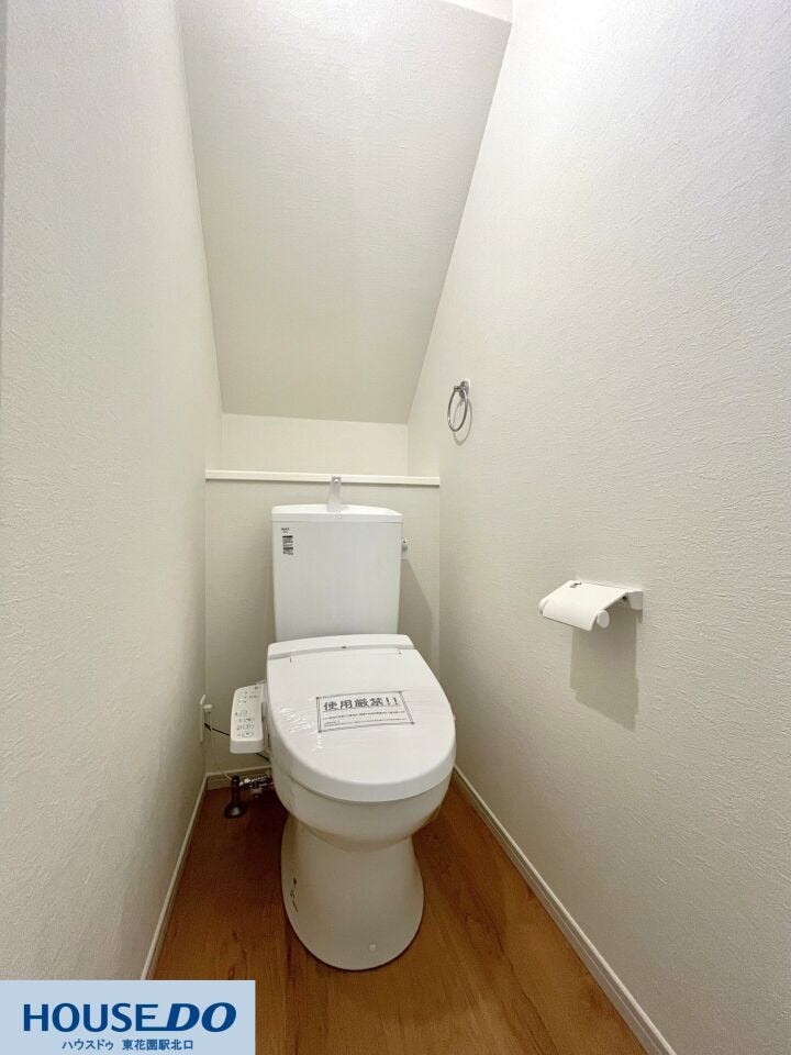 階段下のスペースを有効活用した、無駄のない設計のトイレです。温水洗浄便座を完備しており、毎日快適に使用可能。白を基調とした内装と木目調の床が、清潔感のある落ち着いた空間を作り出しています。