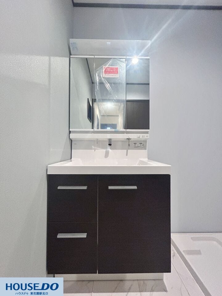 白を基調とした清潔感のある洗面室です。三面鏡の裏側はすべて収納になっており、散らかりがちな洗面小物もすっきりと片付きます。大理石調のフロアは水に強く、日々のお掃除も手軽に行える実用的な設計です。