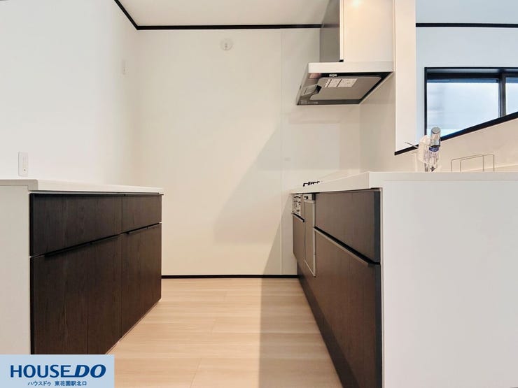 キッチンの背面には、調理家電や食器を整理しやすい大型のカップボードを配置。通路幅にもゆとりがあり、複数人での作業も快適です。ダークトーンのパネルが空間を引き締め、落ち着いた印象を与えます。