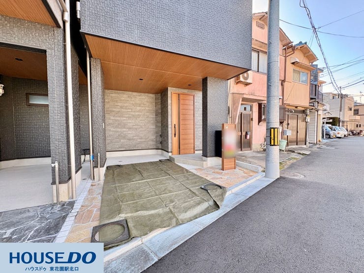 玄関先には、雨の日でも濡れにくい屋根付きの駐車・駐輪スペースを備えています!シックなグレーの外壁と木目調のドアが調和したモダンな佇まいで、足元には滑りにくい石畳風のタイルが敷き詰められています♪