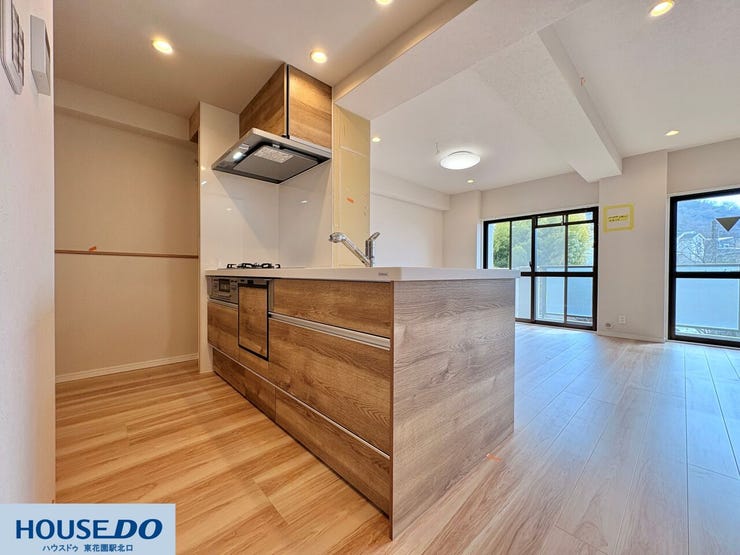 木目パネルが印象的な、収納力のあるシステムキッチンです。スライド式の引き出しは奥の物まで取り出しやすく、重い鍋の出し入れもスムーズ。対面式のため、窓からの景色やテレビを眺めながら楽しく調理ができます。