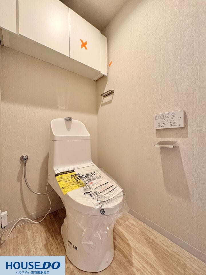 清潔感のあるホワイトの壁紙と、温かみのある床材を組み合わせた落ち着いた空間です。リモコンは壁掛けタイプで操作しやすく、凹凸の少ない便器デザインと合わせて、日々の拭き掃除がスムーズに行えるのが魅力です。